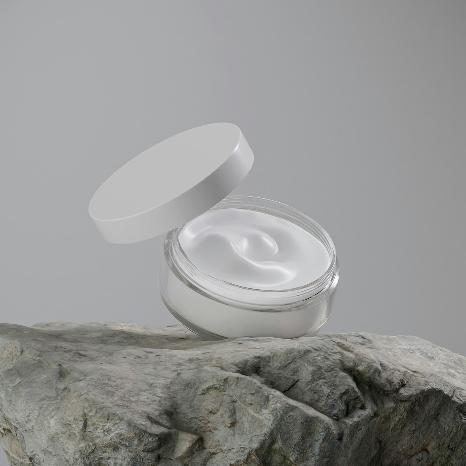 Open jar of thick white cream resting on a grey rock