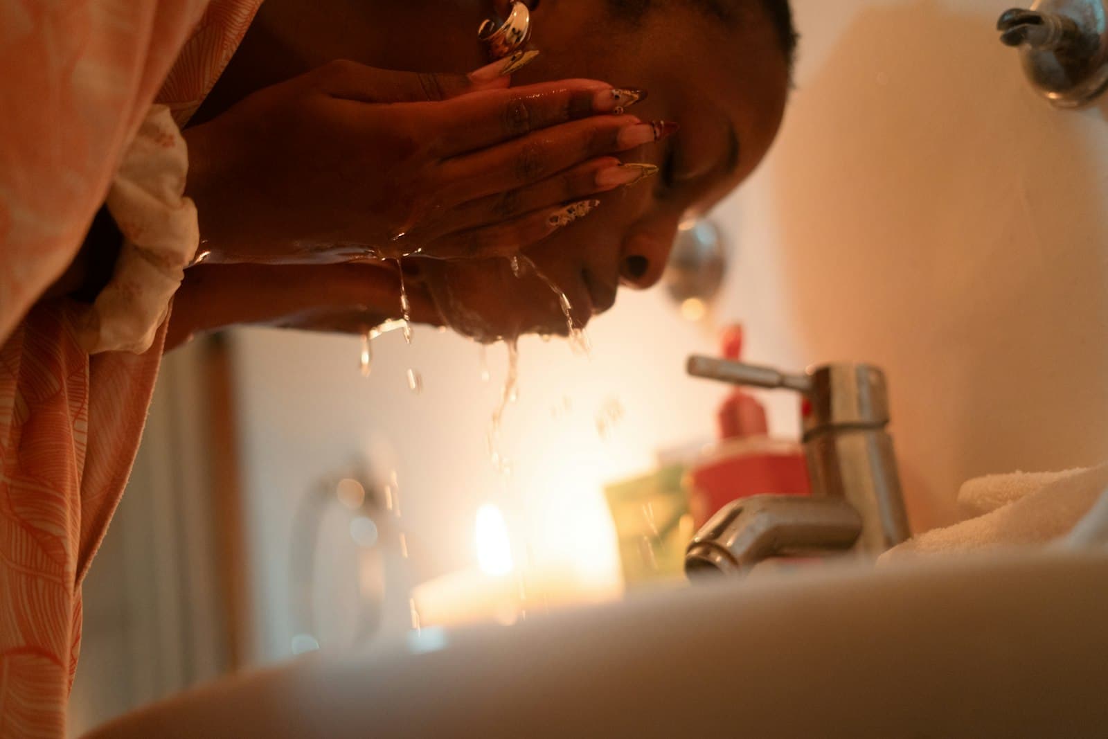 Woman splashing water on her face at a bathroom sink