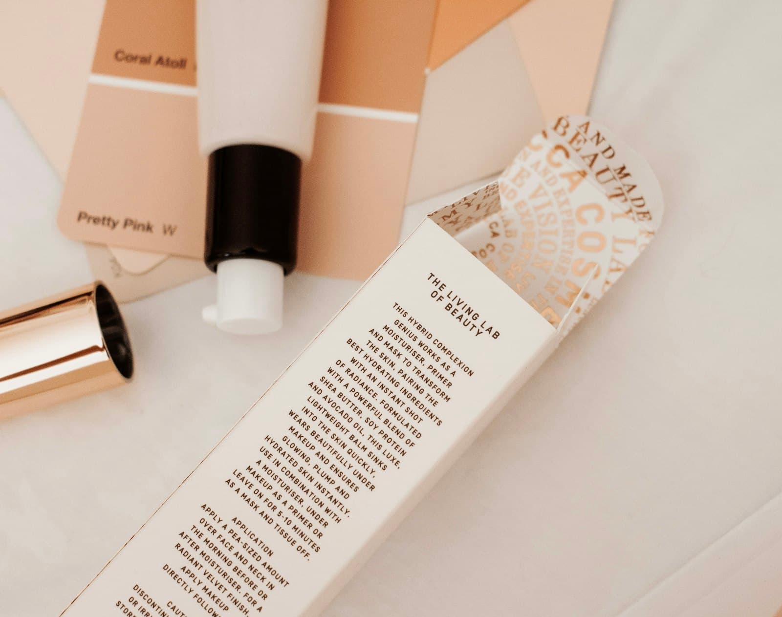 Skincare tube beside its open printed box with small text, laid on white fabric