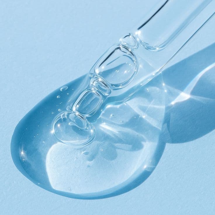 Clear serum dropper bottle surrounded by floating bubbles on a blue background