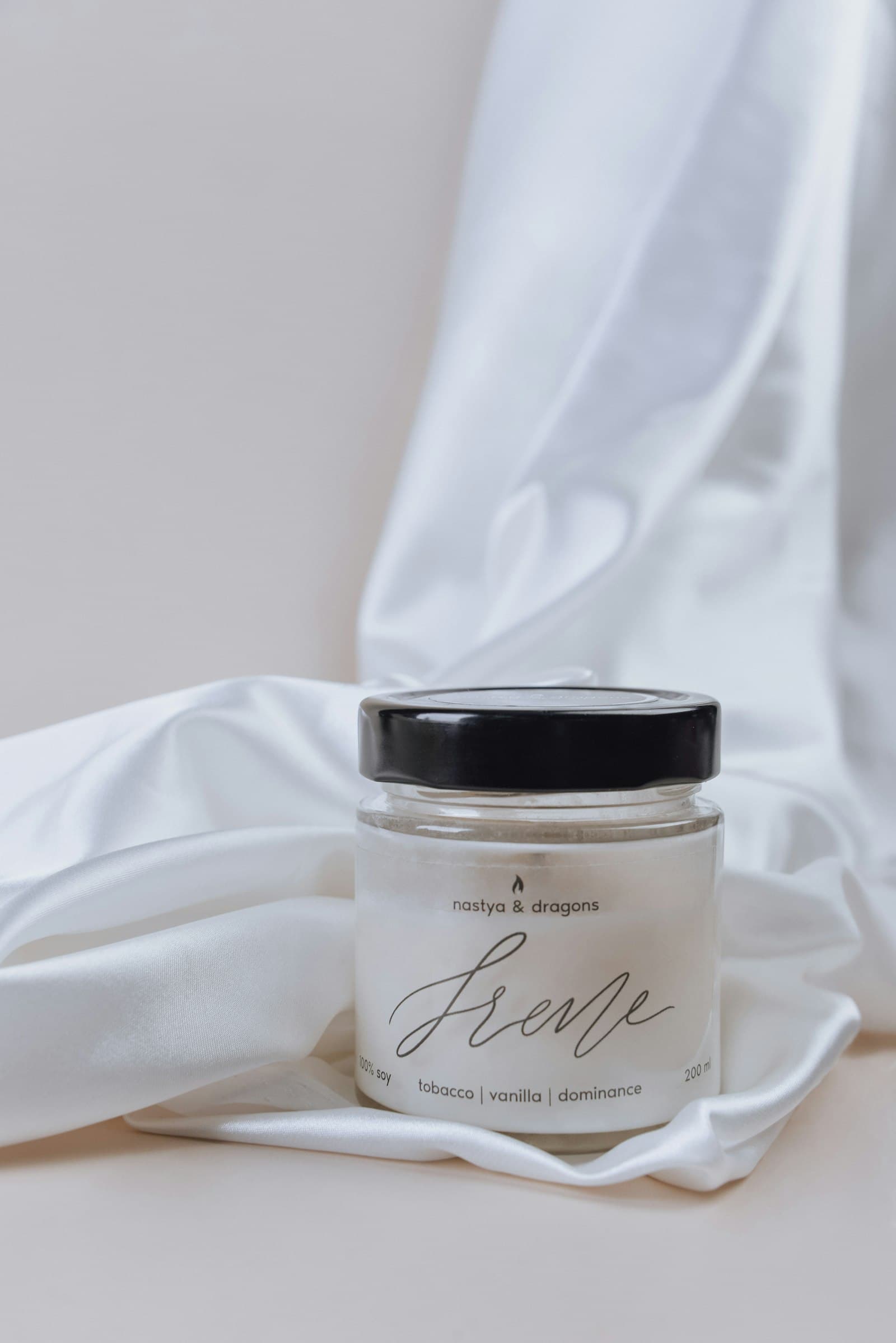 Simple glass jar of cream resting on soft draped white fabric
