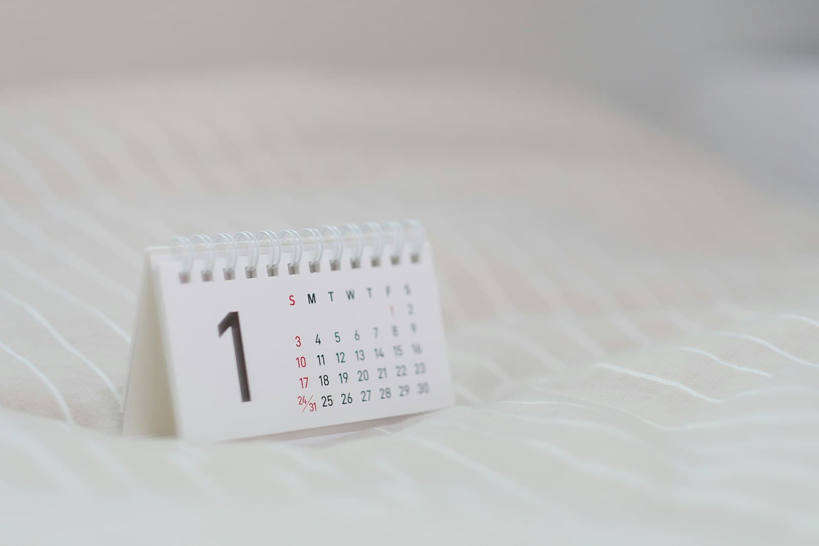 Small white desk calendar standing on soft white bedding