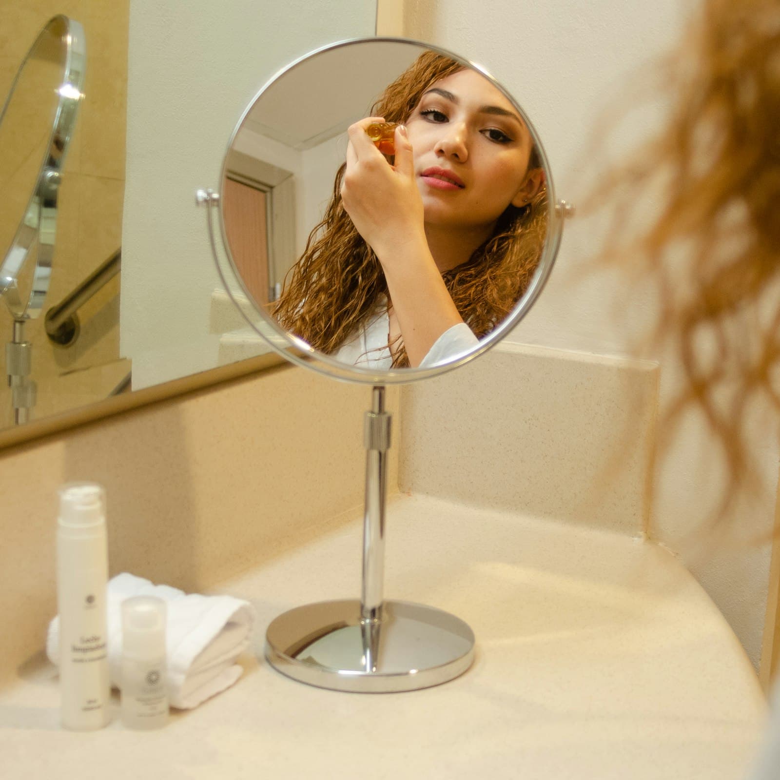 Woman checking her skin in a round magnifying mirror on a bathroom counter