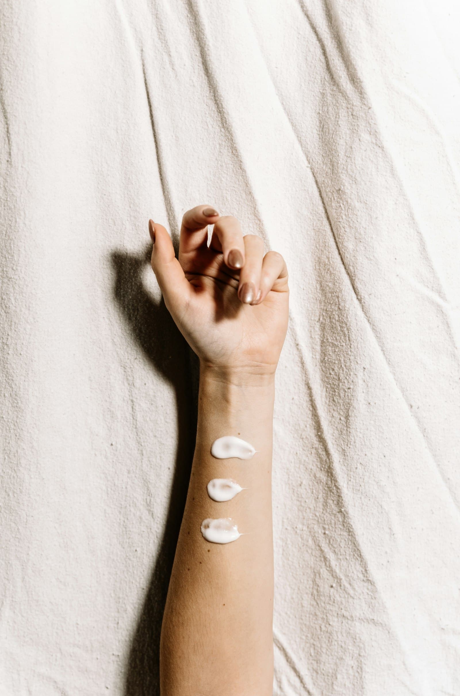 Three small dabs of white cream on the inner arm, like a skincare patch test
