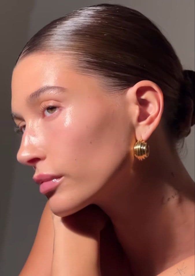 Woman with dewy, glowing skin and eyes closed in bright sunlight
