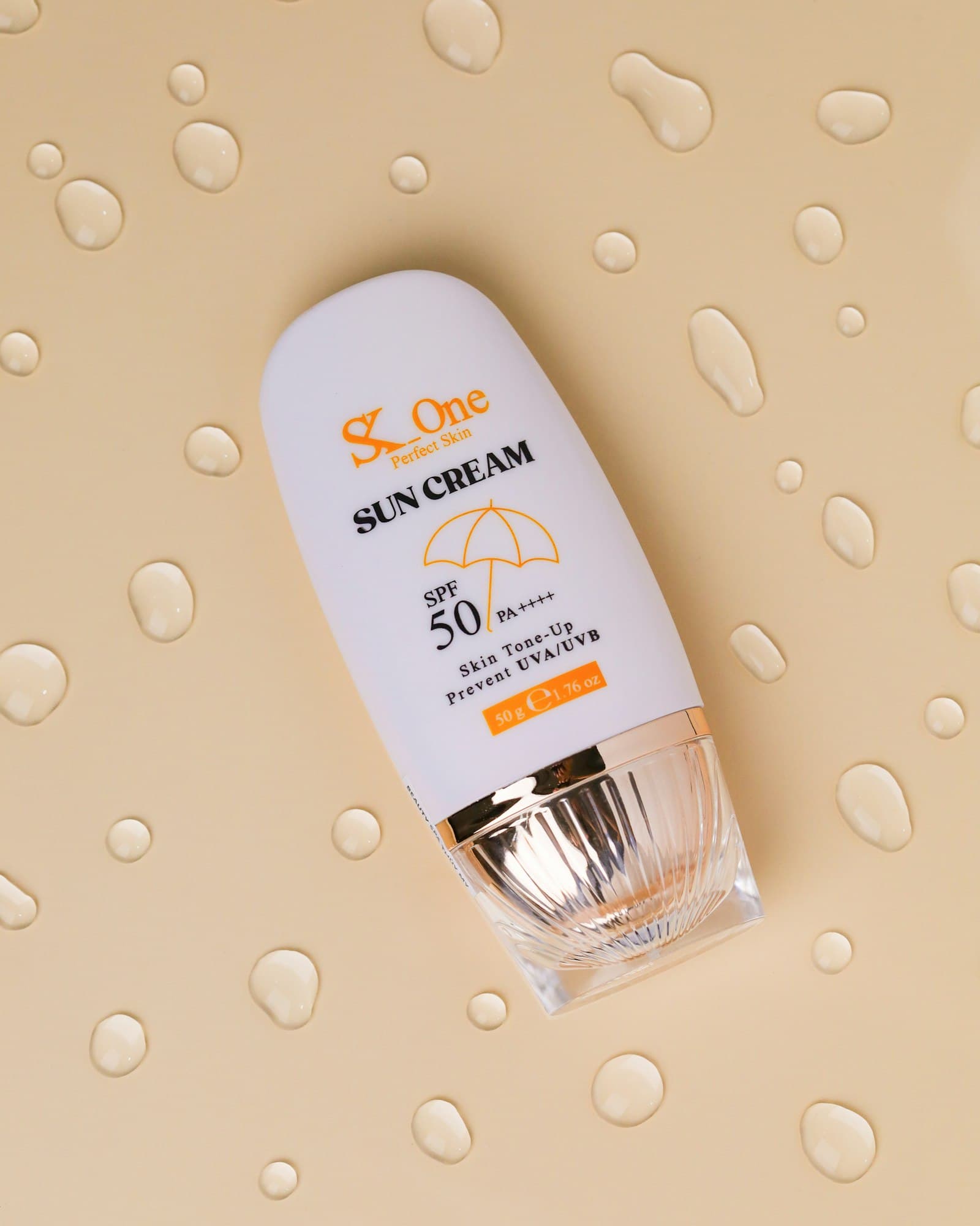 Bottle of SPF 50 PA++++ sun cream lying on a beige surface scattered with water droplets