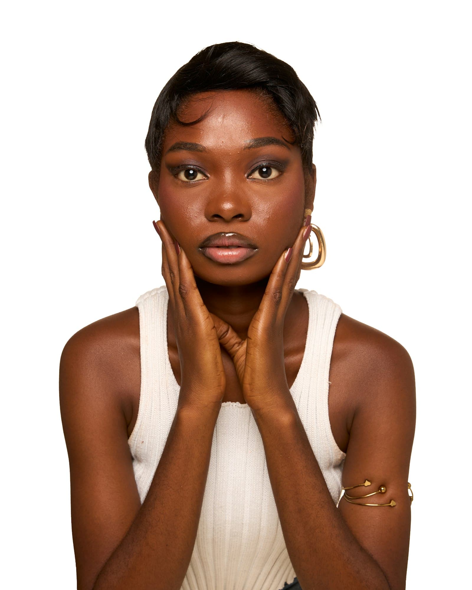 Woman gently cupping her face with both hands against a white background