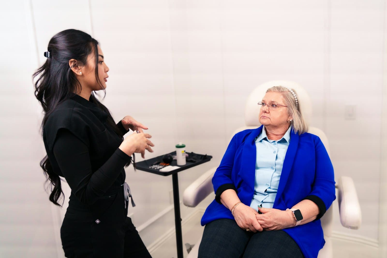 Skin care professional talking with a seated client in a bright clinic room