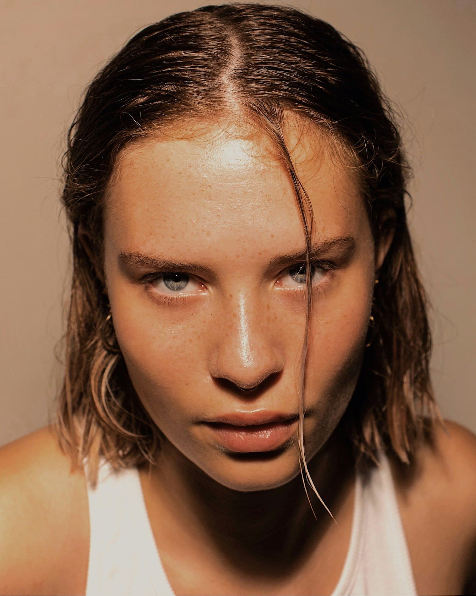 Woman with slicked-back hair and visible shine across her forehead, nose and cheeks